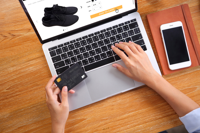 Business woman using credit card for buy black running shoes on