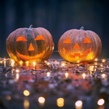 two-smiling-halloween-pumpkins-wooden-table-with-lights-mystic-forest-night_213438-941